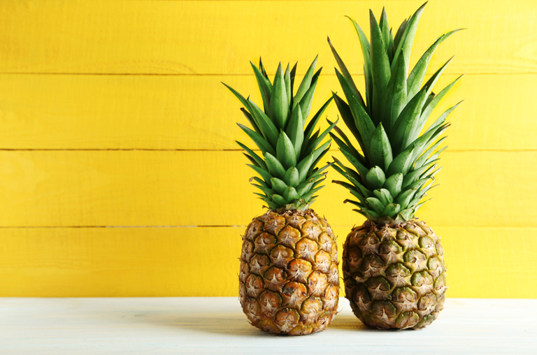 Zwei frische Ananas vor einer gelben Wand