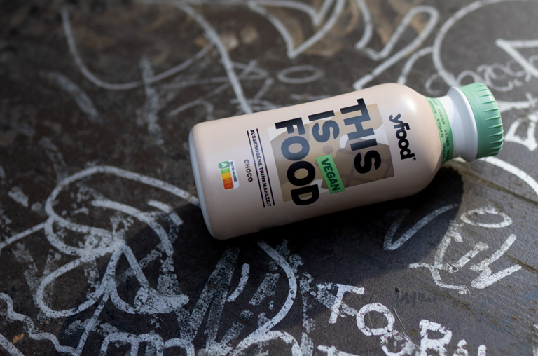 Eine Flasche YFood Choco, platziert auf einem mit Graffiti bemalten Tisch. Foto: yfood
