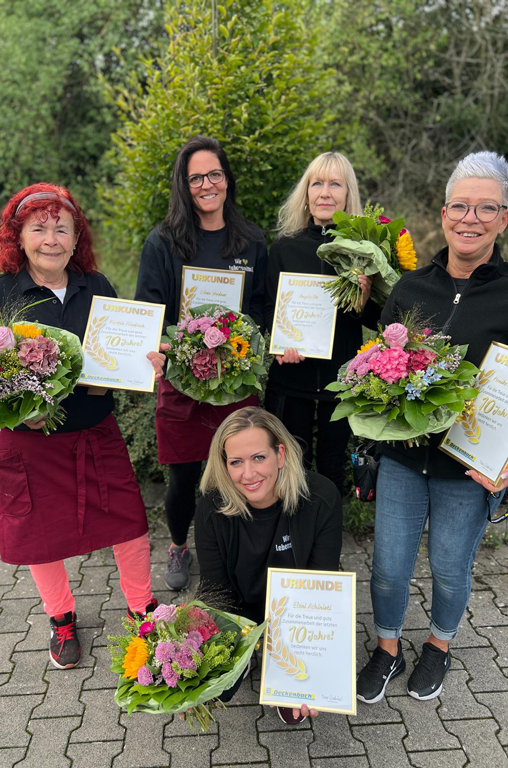 Feierten vor Kurzem ihr 10. Jubiläum bei EDEKA Deckenbach und bekamen von Marktinhaber Frank Deckenbach einen Blumenstrauß sowie eine Urkunde überreicht: (v. l.) Kerstin Friedrich, Eileen Weidner, Eleni Athinioti (hockend), Angela Ott und Monika Pschierer. Es fehlen: Stefanie Klemenz und Simone Rapp. 