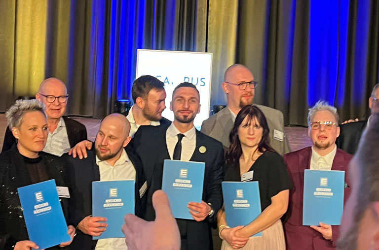 Deniz Yolcu (Bildmitte) präsentiert bei der EDEKA-Abschlussgala stolz sein Abschlusszertifikat